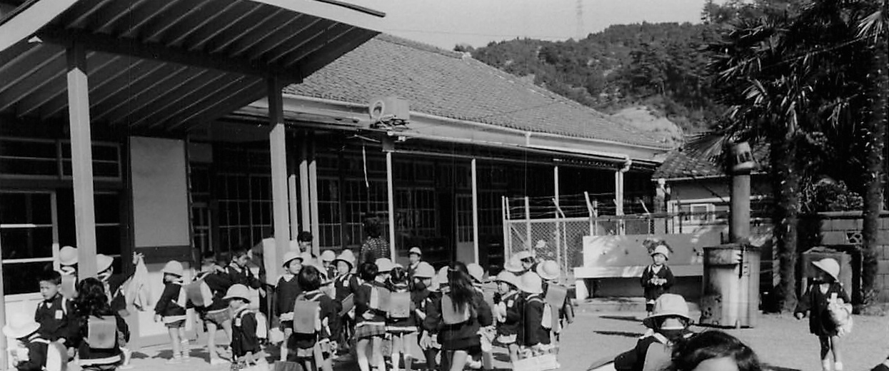 袖師保育園の歴史を感じる白黒写真です。園舎の前に子どもたちがたくさんいます。