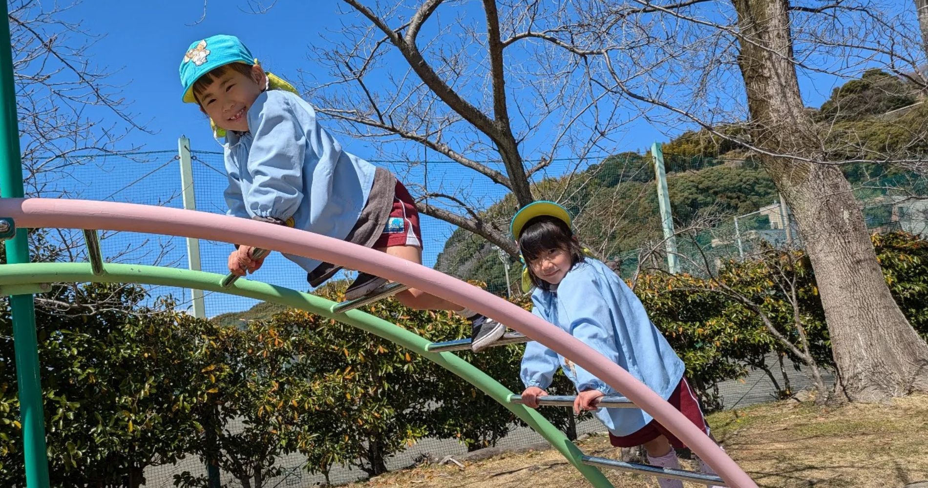 4歳児のこどもが2人、公園の遊具で遊んでいます